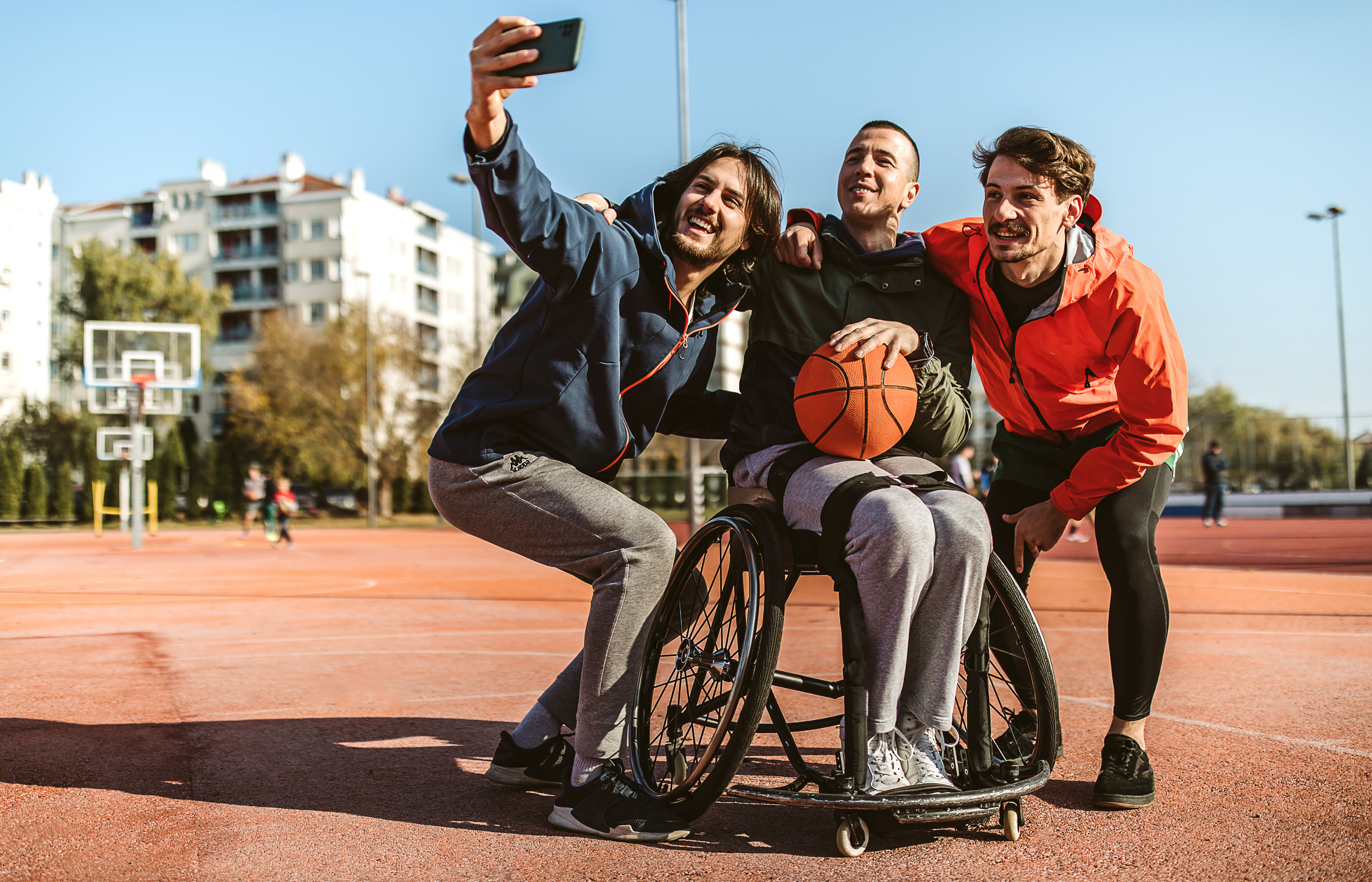 selfie of friends at basketball court, one friend in wheelchair