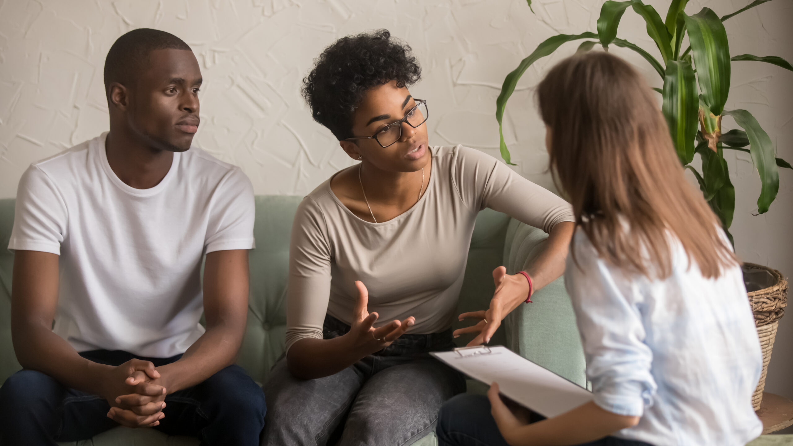 man and female sitting on couch speaking with a doctor