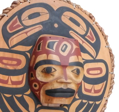 Masque autochtone en bois sur lequel est peint un oiseau rouge et noir.