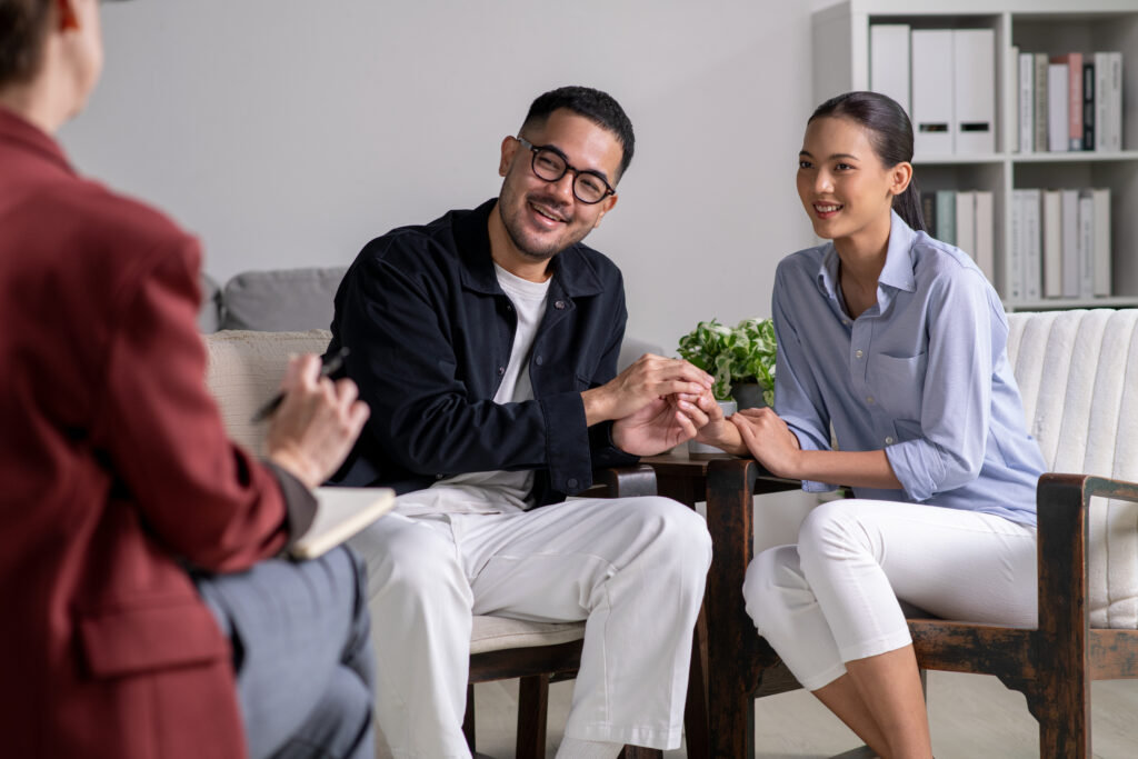 Happy Young Asian couple talking and consulting therapist