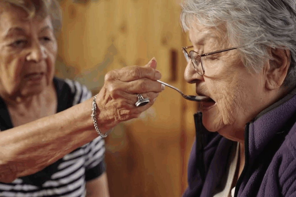 Photo of two women as a part of the caregiver series where in one of the videos they demonstrates how you can help someone with eating and drinking.