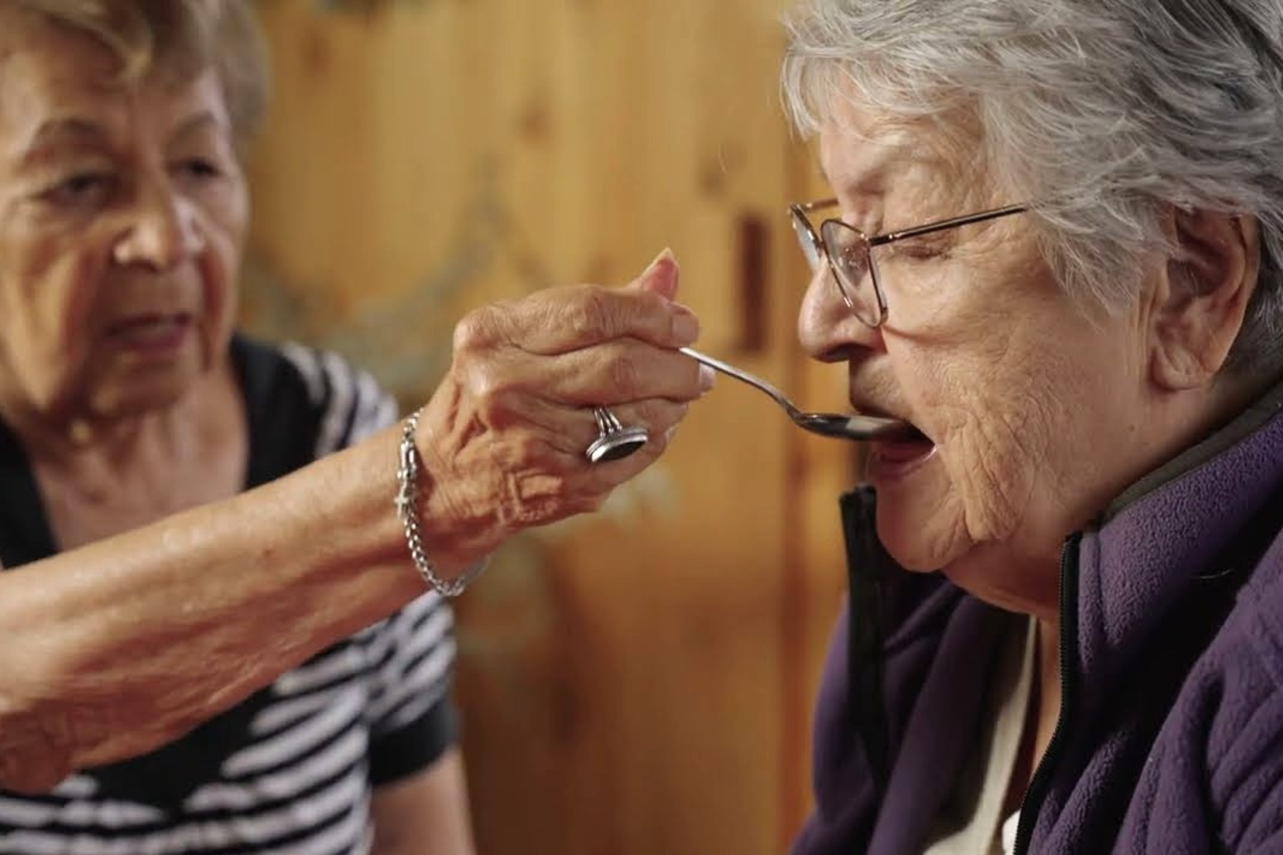 Photo of two women as a part of the caregiver series where in one of the videos they demonstrates how you can help someone with eating and drinking.